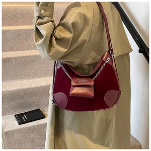 Detalle de bolso creciente en terciopelo granate con mini monedero y cadena