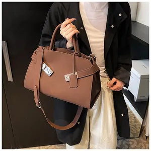Detail of brown leather handbag with silver metallic lock and adjustable shoulder strap