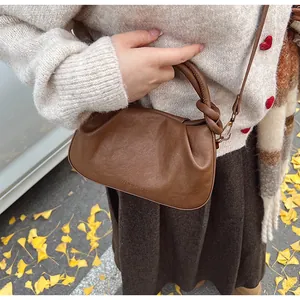 Détail d'un sac à main plissé marron foncé avec l'inscription Fashion & Bags gaufrée