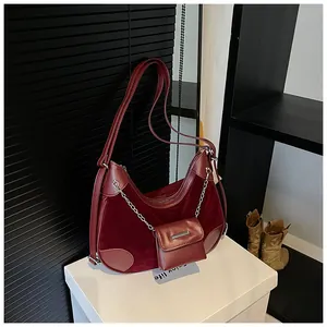 Detalle de bolso medialuna en terciopelo granate con cadena plateada y mini estuche
