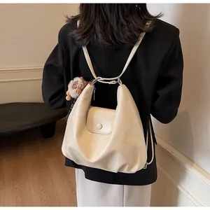 Dettaglio dello zaino hobo in morbida pelle beige con chiusura a patta e ciondolo a orso