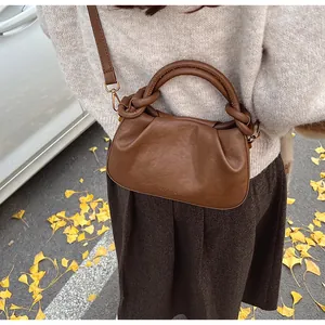 Détail du sac dumpling plissé caramel montrant la poignée nouée et les crochets