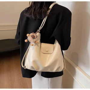 Dettaglio della grande borsa tote bianco crema opaco con ciondolo a forma di orso