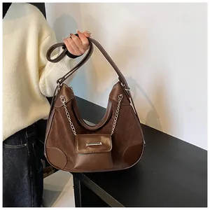 Detalle de bolso tote de ante marrón oscuro con cadena plateada y mini estuche colgante