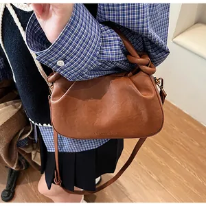 Détail du sac à main plissé marron caramel avec poignée nouée et texte fashion