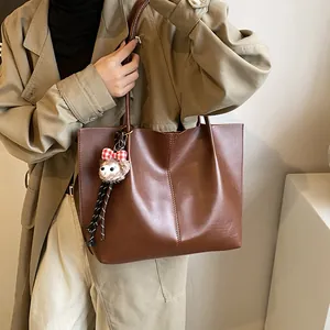 Deep brown minimalist tote bag in smooth leather with a cute sheep plush charm on the strap