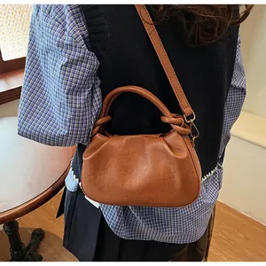 Détail du sac à main marron plissé avec poignée nouée et logo imprimé élégant