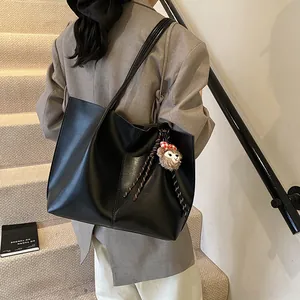 Minimalist black PU leather tote bag with long shoulder strap and bear charm accessory