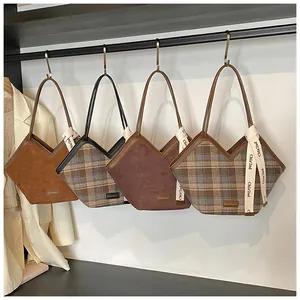 Detail view of four textured plaid and suede tote bags hanging on a rack in a closet