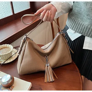 Close-up of the pleated texture and tassel detail on the light brown tote bag