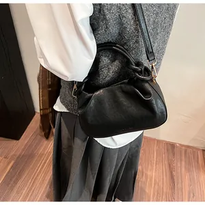 Gros plan d'un sac nuage plissé noir avec bandoulière porté par un mannequin en style décontracté