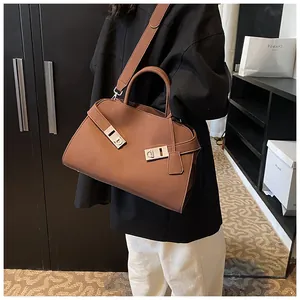 Brown leather tote bag styled as a crossbody bag with distinct gold metal buckles