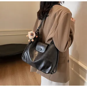 Dettaglio della borsa tote nera in pelle vintage con un ciondolo a forma di orso sulla tracolla