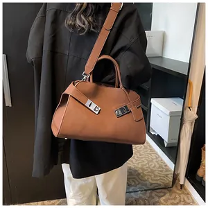 Detailed view of a brown leather handbag with silver metallic buckles and crossbody strap