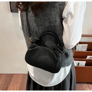 Détail du sac plissé noir montrant le cuir PU brillant et la poignée torsadée