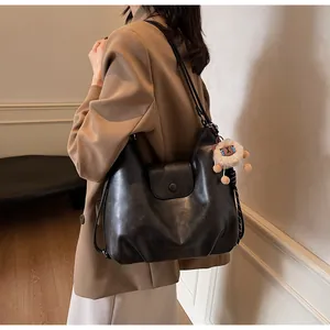 Dettaglio borsa hobo vintage nera con ciondolo in peluche indossata a spalla