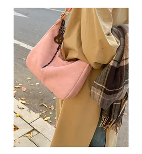 Detail of pink faux suede shoulder bag with striped rope and stylish round charm