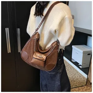 Detalle del bolso tote de media luna marrón con cadena de metal y pequeño sub-bolso