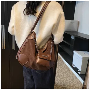Detalle de bolso tote de ante marrón con mini bolso y cadena sobre el modelo