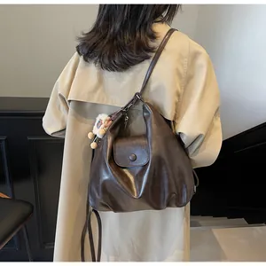 Dettaglio della borsa a spalla vintage in pelle marrone scuro con un ciondolo di peluche