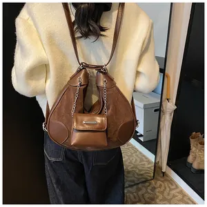 Detalle de un bolso tote marrón oscuro con doble bolsa, cadena y texturas de cuero mixto