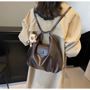 Dettaglio di zaino in pelle plissettata marrone scuro con portachiavi in peluche alpaca