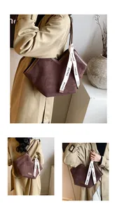 Detailed view of the deep brown suede tote bag with V-shaped cut and branded white ribbon