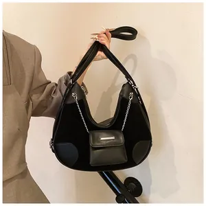 Detalle del bolso tote de cuero negro y ante con una mini bolsa decorativa de cadena