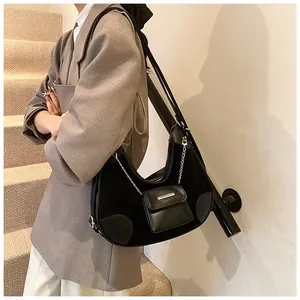 Detalle de bolso bandolera media luna negro en ante con monedero decorativo de cadena metálica