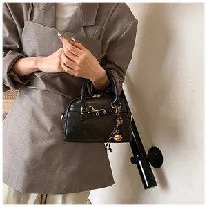 Detail of a vintage black Boston bag with gold horsebit hardware and textured leather