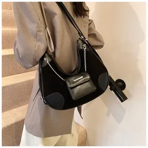 Detalle de bolso medialuna negro con cadena plateada y mini monedero colgante elegante