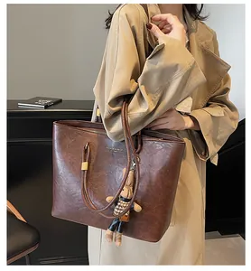 Détail du cabas en cuir marron foncé avec un porte-clés ours en peluche sur la bandoulière