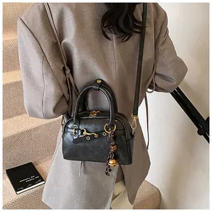 Detail of a black leather handbag with gold hardware and a tassel on a stylish model