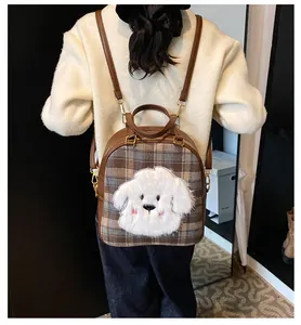 Detail of checkered backpack featuring a 3D plush puppy and brown leather straps