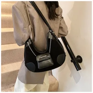 Detalle de bolso tote patchwork negro con mini monedero de cadena y detalles en cuero