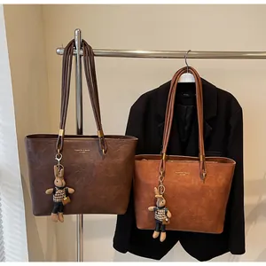 Vue détaillée des sacs cabas vintage en cuir souple avec marquage doré et pendentif lapin