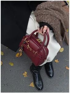 Detail of burgundy leather Boston bag with gold hardware and woven rope accessory
