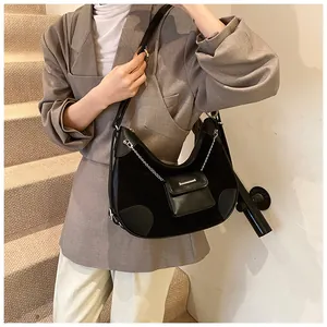 Detalle de bolso hobo negro con cadena plateada y pequeño estuche llevado por modelo
