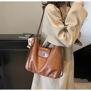 Dettaglio borsa hobo marrone in pelle vintage con patta e ciondolo a forma di pecora