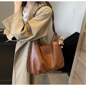 Borsa tote vintage marrone con ciondolo di peluche indossata da una modella con trench