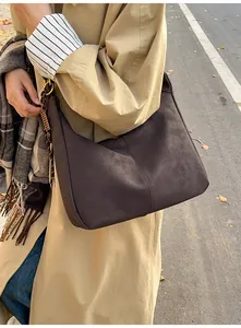 Detail of dark brown matte leather tote with vertical stitching and tassel ornament