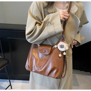 Borsa tote marrone in ecopelle con ciondolo a pecorella bianca indossata su un trench