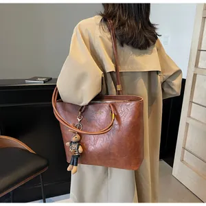Détail du cabas en cuir marron vintage avec logo doré et breloque lapin en peluche