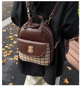 Detail of vintage plaid mini backpack with teddy bear patch on an outdoor park bench