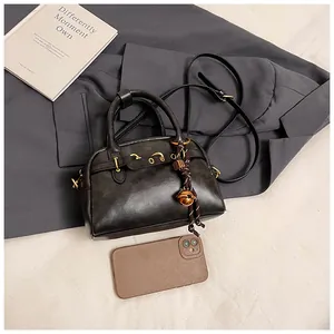 Detail of vintage grey Boston bag showing matte leather texture and gold bell charm accessory