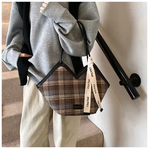 Detail of plaid tote bag with V-shaped opening and decorative ribbon on shoulder