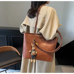 Détail du sac cabas vintage en cuir marron avec lettrage et pendentif lapin mignon