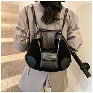 Detalle de bolso tote de ante negro con cadena plateada y pequeño bolso exterior fijo