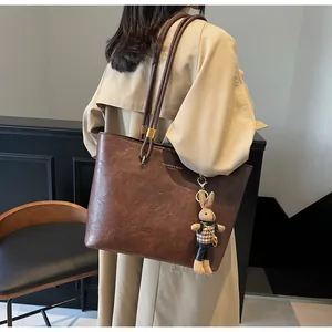Détail du cabas vintage marron avec texture cuir, pendentif lapin et garnitures en métal