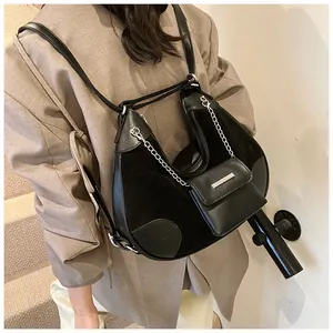 Detalle de bolso tote negro de materiales mixtos con cadenas y monedero pequeño